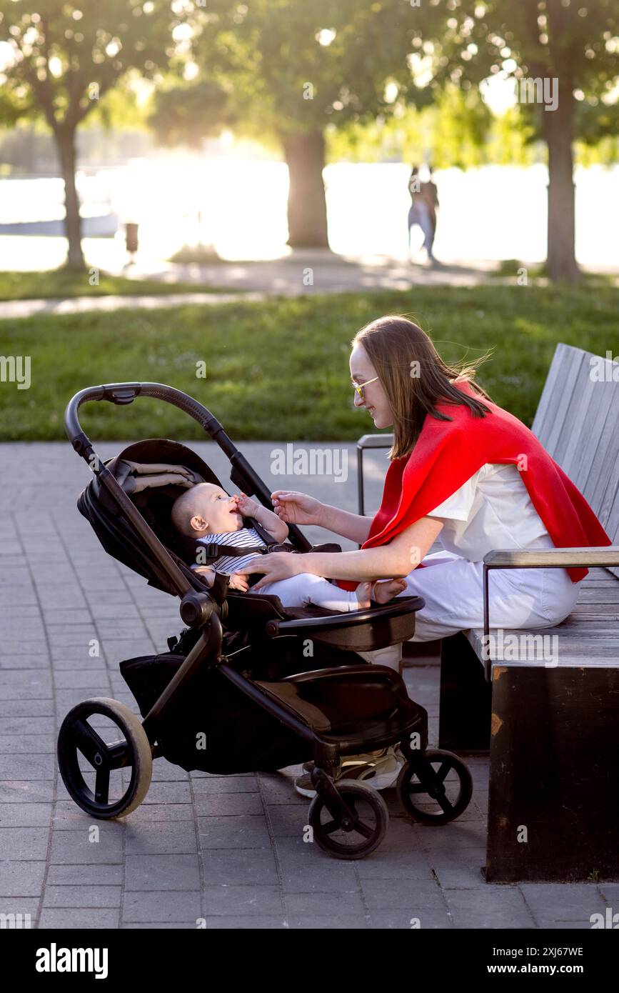 Young mother with her cute baby is sitting on a park bench Stock Photo ...
