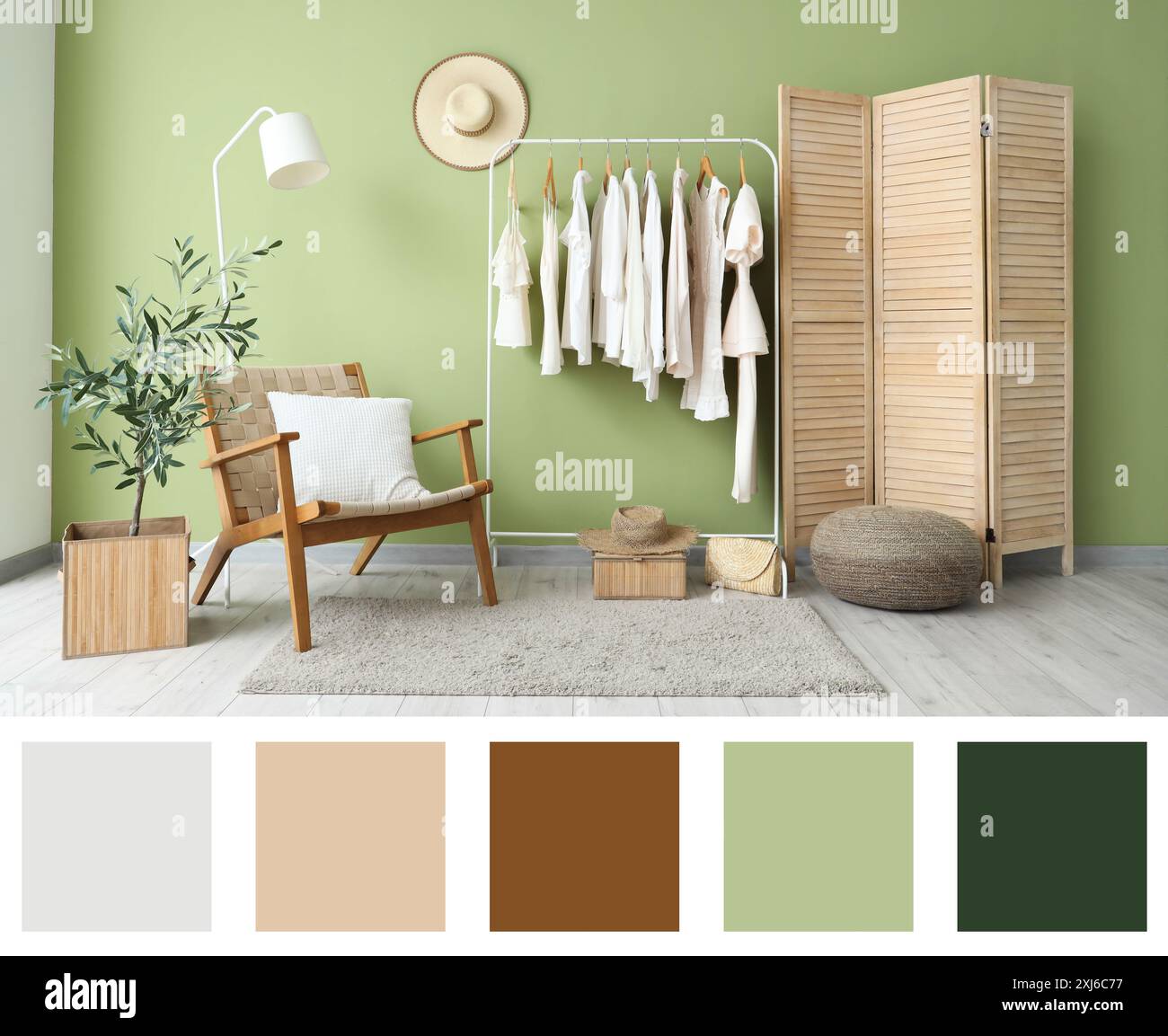 Rack with stylish clothes, armchair and folding screen near green wall ...