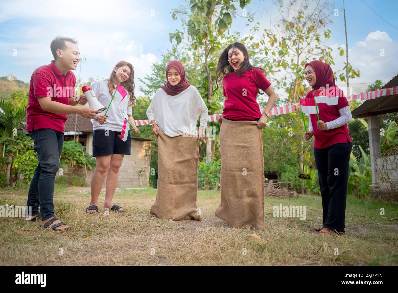 A group of people are playing a game of tug of war with burlap sacks ...