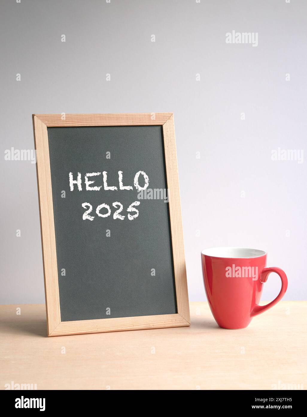 Hello 2025, text on a blackboard next to coffee in red cup. New year. Stock Photo