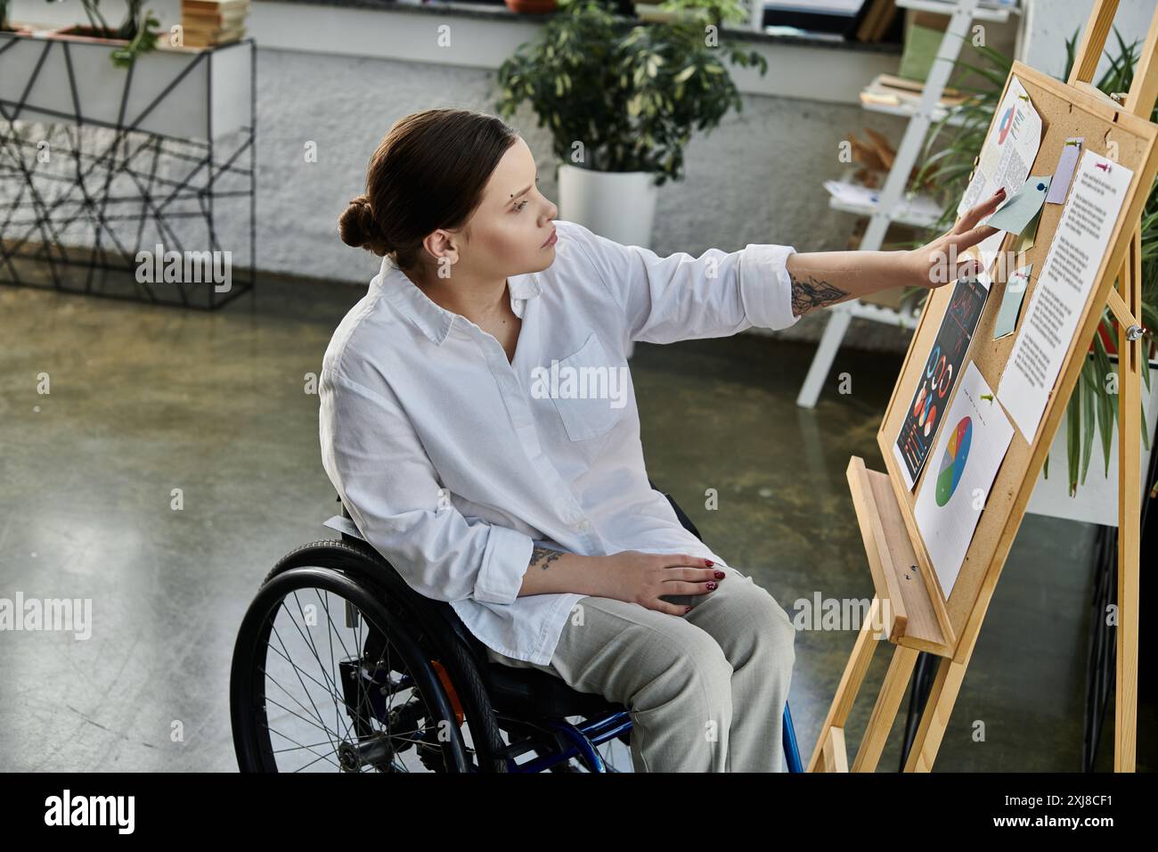 A young businesswoman in a wheelchair works at her desk in a modern ...
