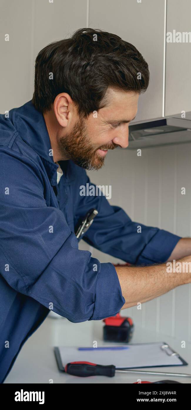 Professional electrician using screwdriver while installing new electrical socket on home kitchen Stock Photo