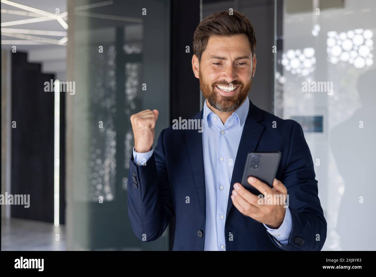 A joyful businessman in a modern office setting celebrates a success ...