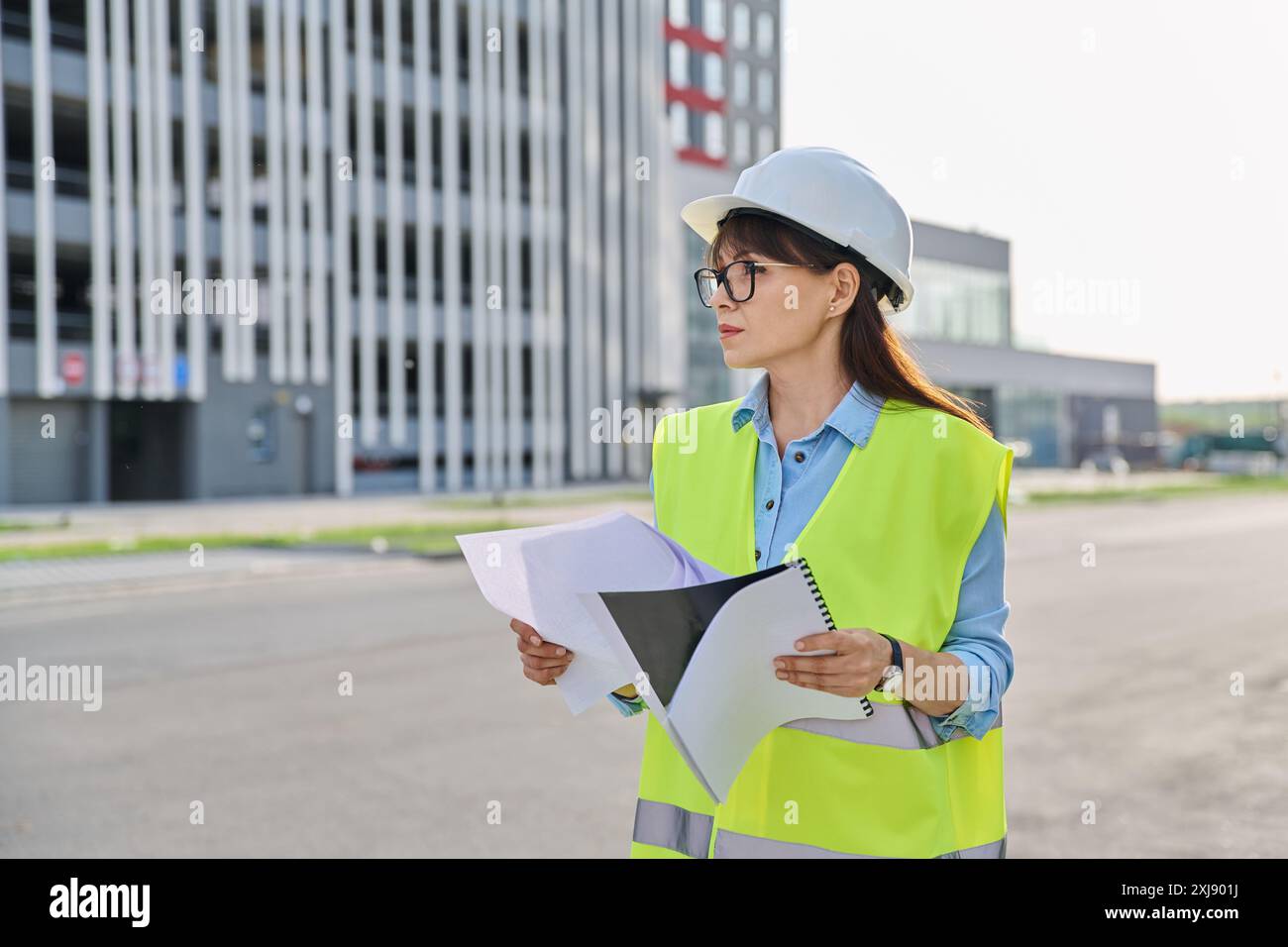 Industrial worker female builder with working documents, outdoor construction Stock Photo