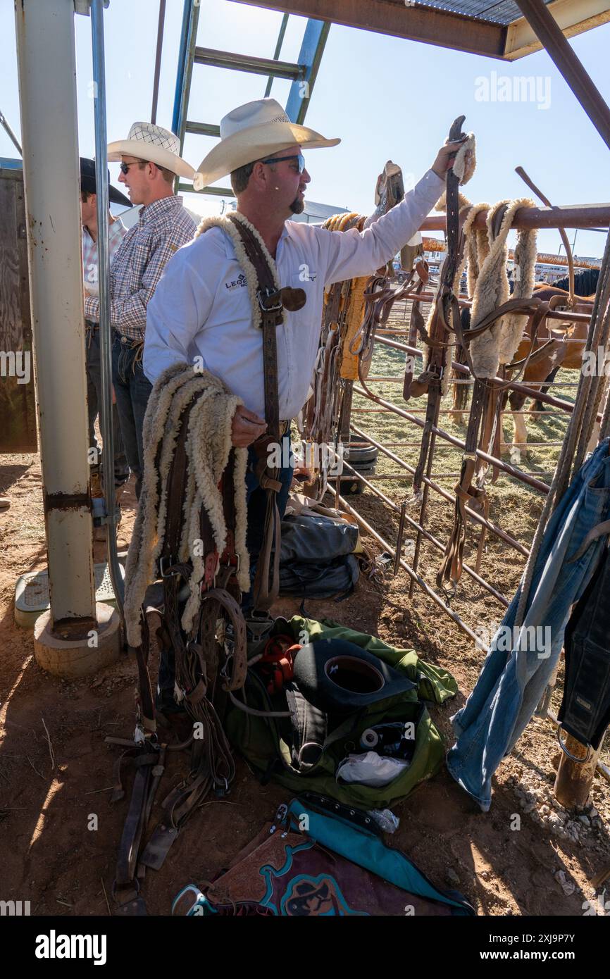 A stock handler hangs up the flank straps for the bucking horses at a rodeo in rural Utah. Stock Photo