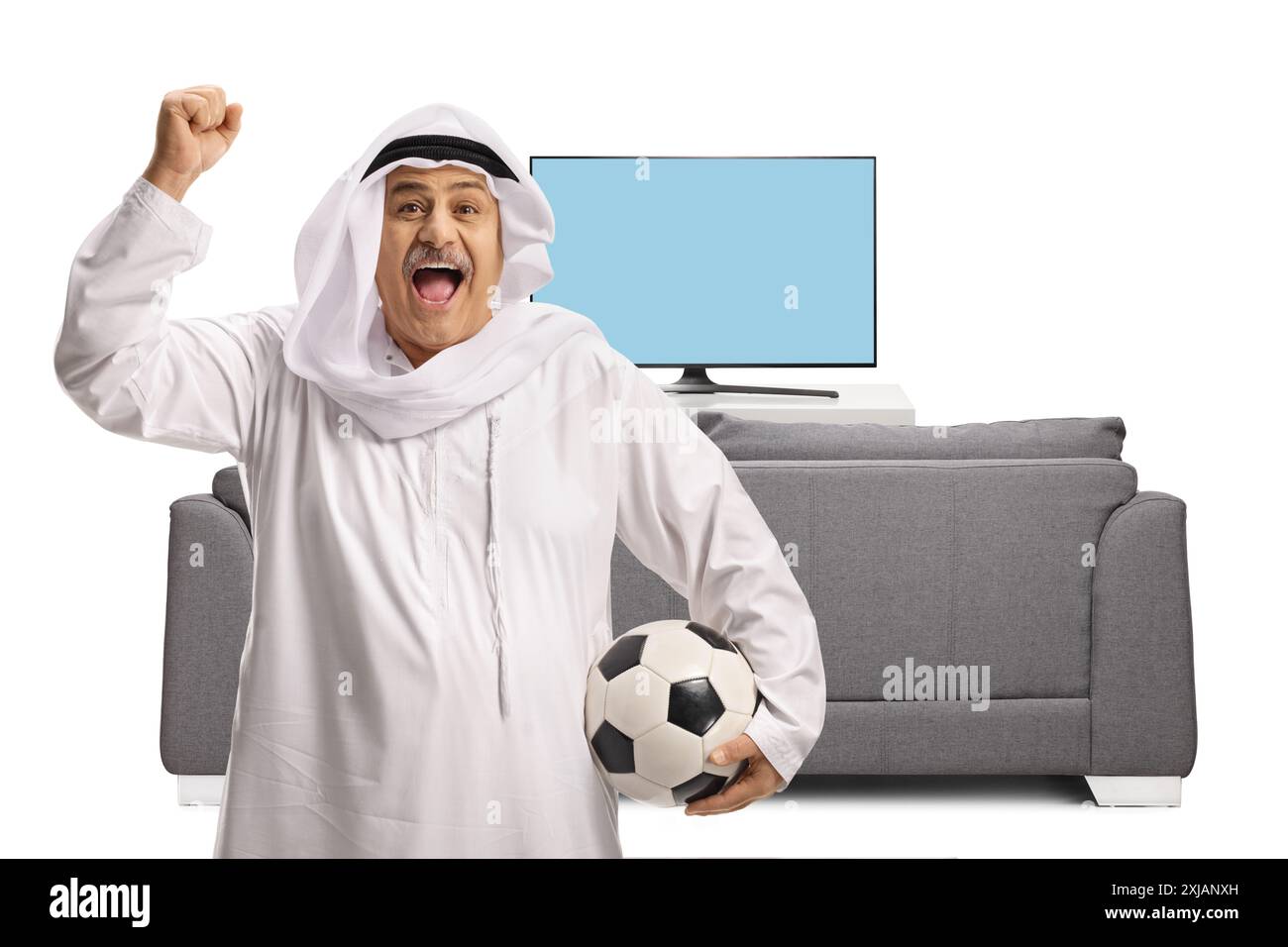 Happy mature arab man with a football cheering in front of tv and sofa ...