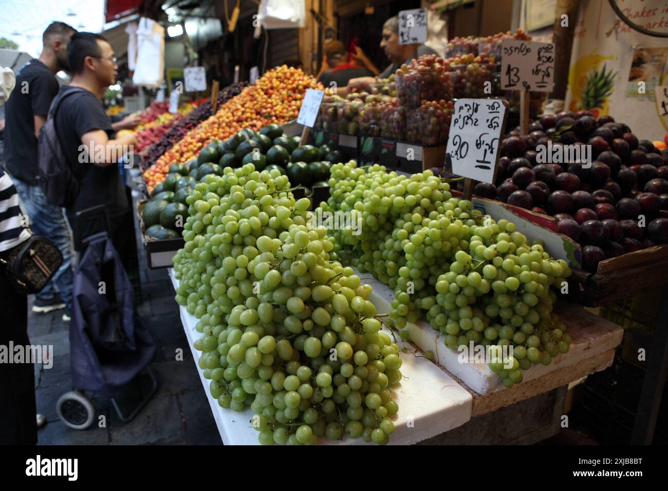 Manchane Two men wearing summer clothes buy fruit at a Machane Yehuda Market ...