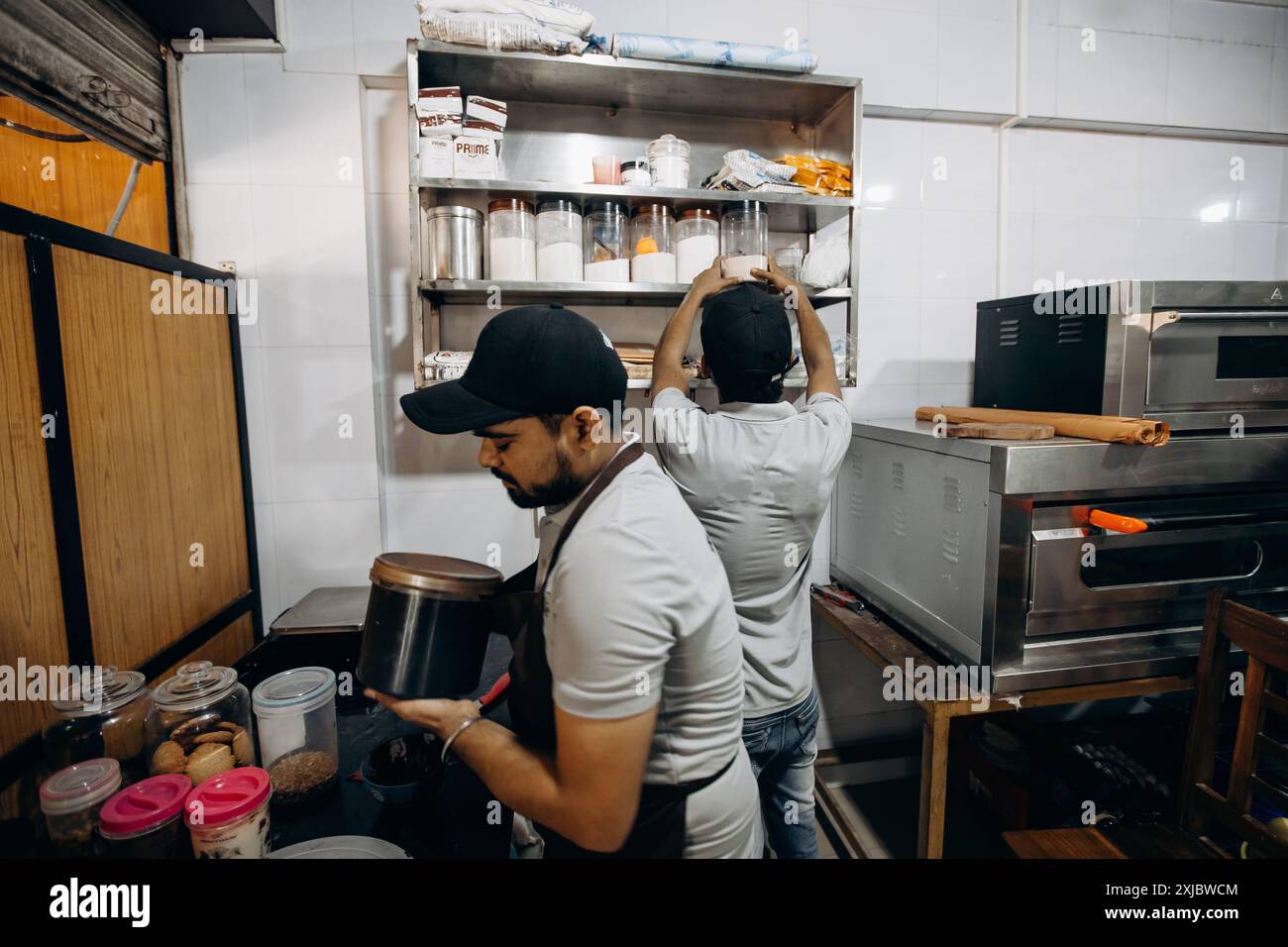 Arrange Ingredients Bakers arrange ingredients in a kitchen using supplies, containers, and ...