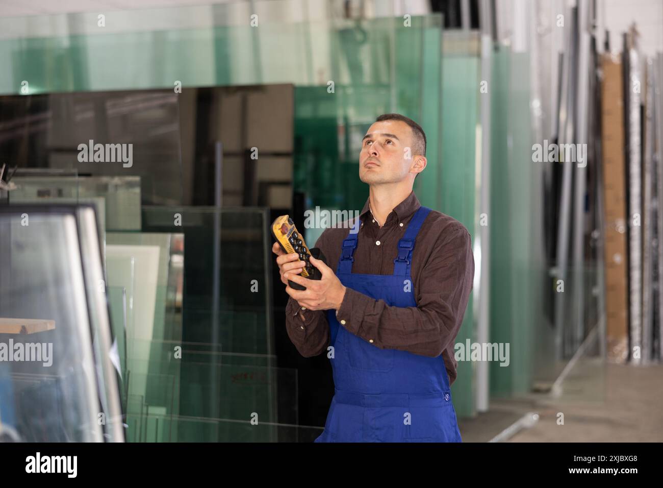 Worker using remote control to operate machinery in glass workshop Stock Photo