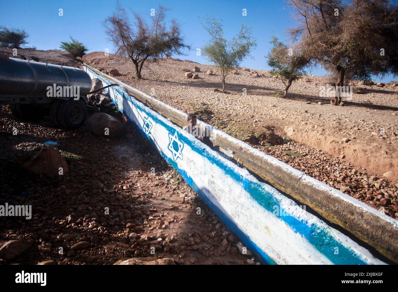 Jordan Valley, Palestine. 17th July, 2024. A Palestinian swims in the Uja River canal marked with an Israeli flag drawn by Jewish settlers to harass Palestinians near the city of Jericho in the northern Jordan Valley. (Photo by Nasser Ishtayeh/SOPA Images/Sipa USA) Credit: Sipa USA/Alamy Live News Stock Photo