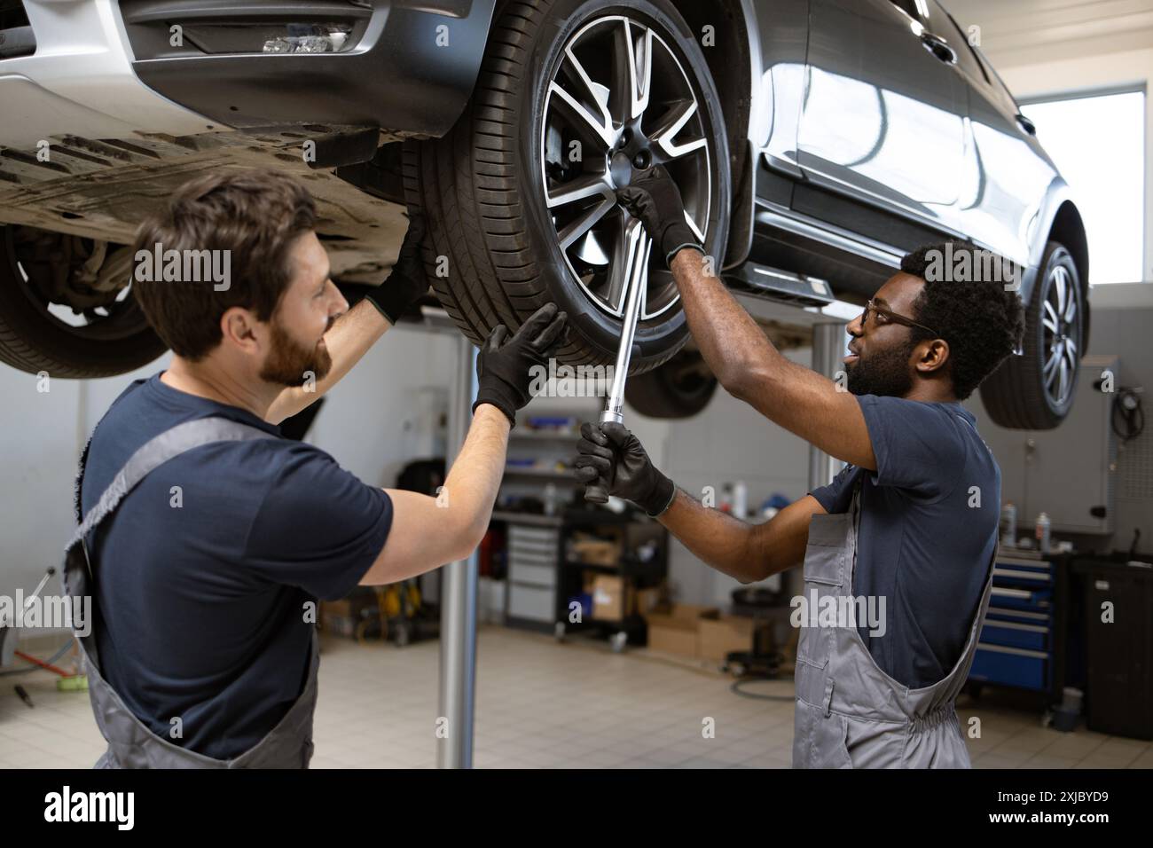 Two mechanics working on car wheel in auto repair shop Stock Photo - Alamy
