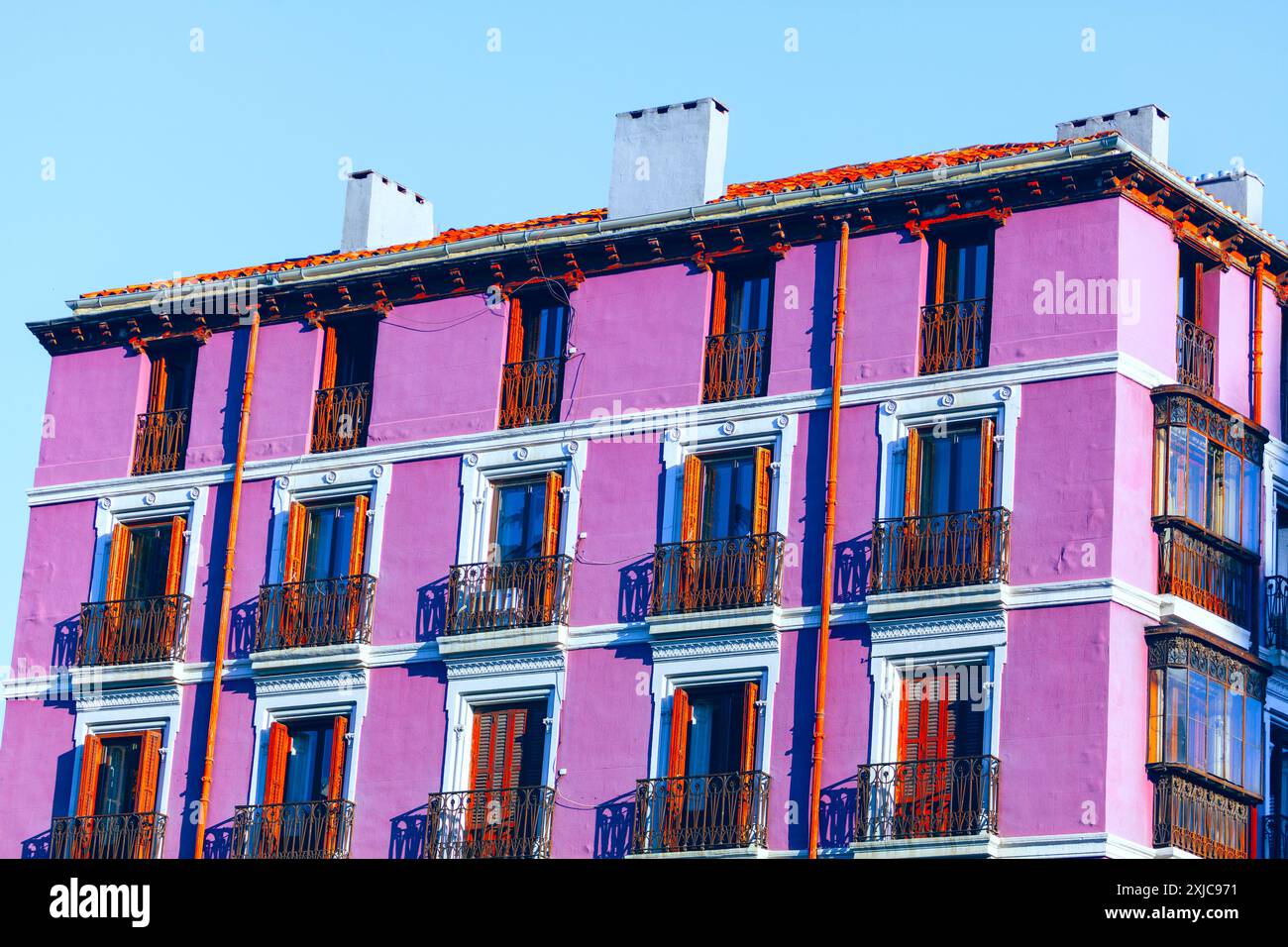Pink building with balconies and windows. House painted in pink adding ...