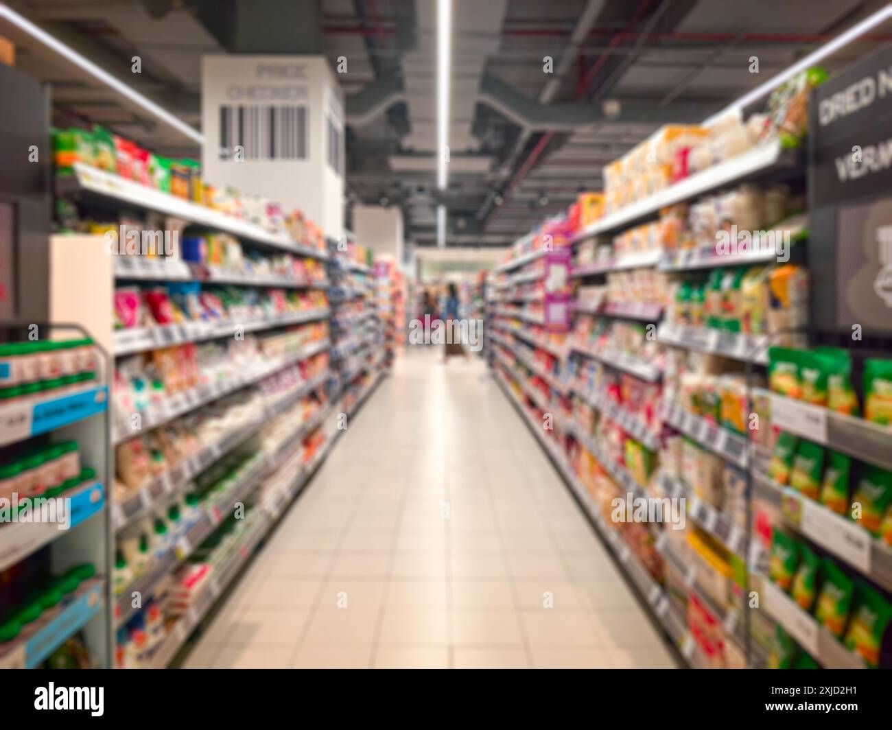 Supermarket aisle with colorful shelves and shoppers. Abstract blur as background. Stock Photo