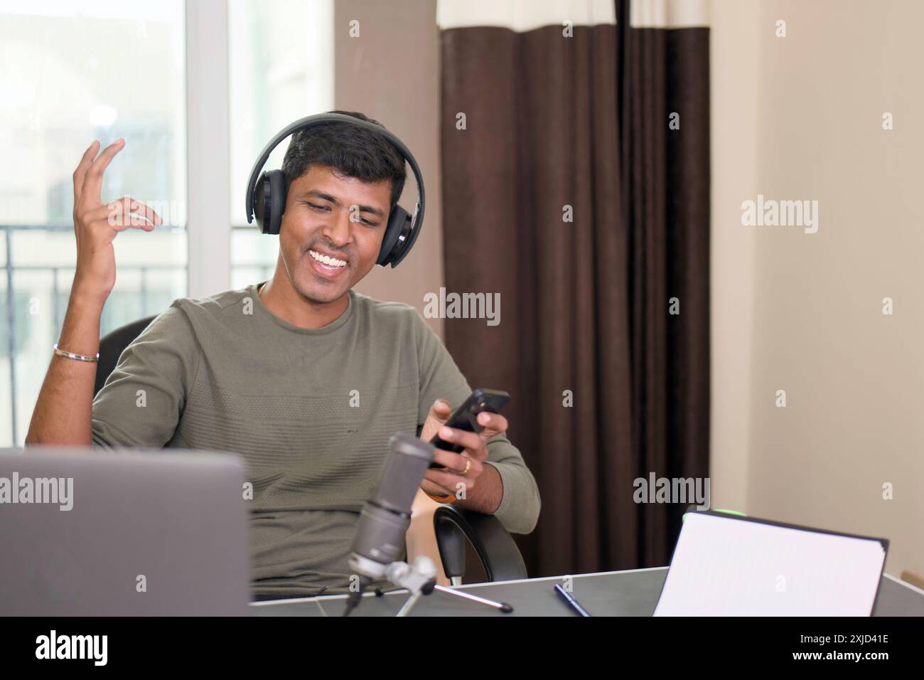 Young man energized and recording a podcast from his home studio. Stock Photo