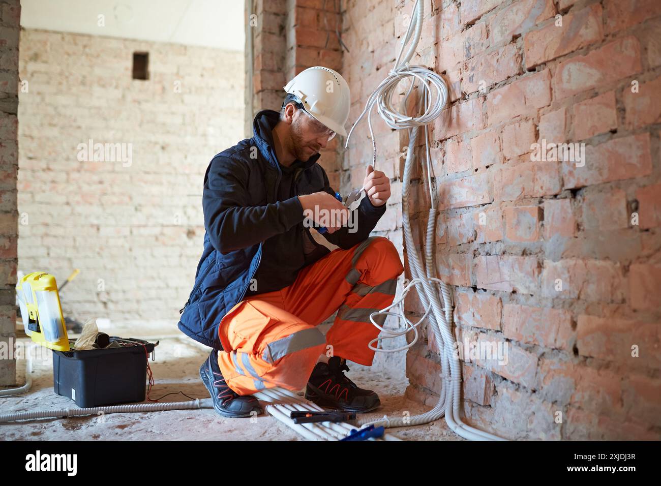 Construction worker installing electrical wiring, using wire cutters