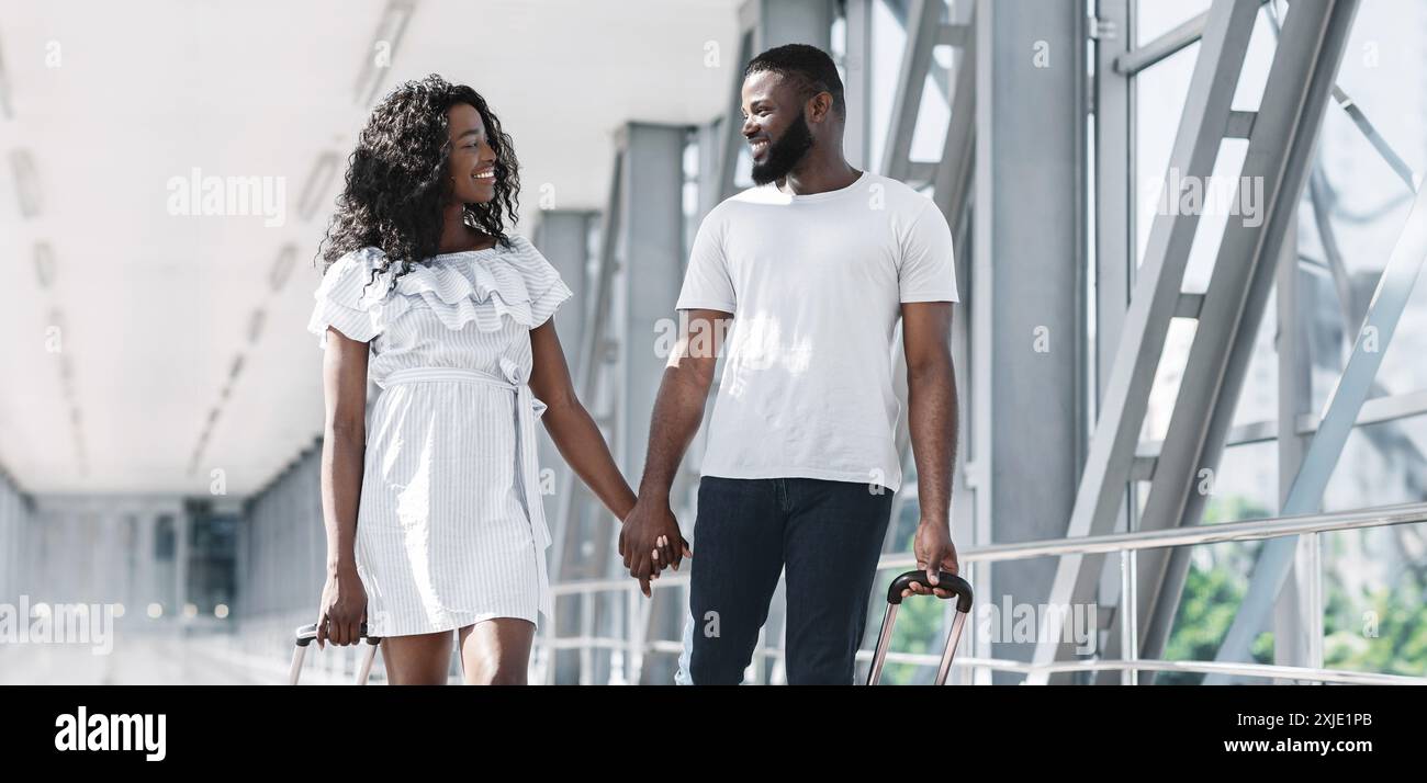 Couple Walking Through Airport Terminal Holding Hands With Luggage ...