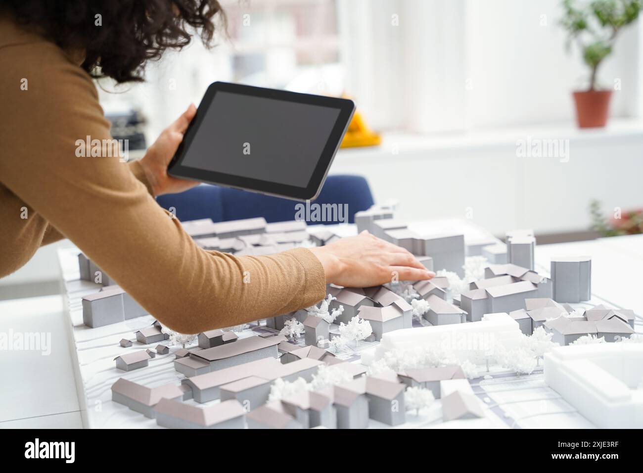 Woman architect using tablet at library table while creating city workout Stock Photo
