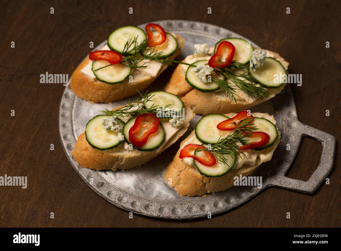 Сheese and cucumber baguette canapes on a metal board. Still life in a rustic style Stock Photo