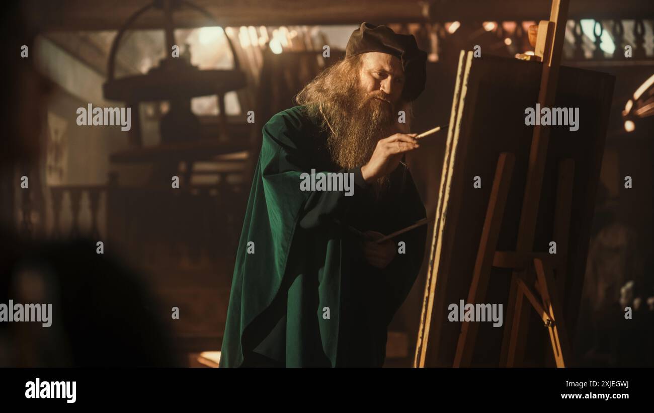 Renaissance Era Concept: Inspired Senior Male Painter Adding Details to his Painting on Canvas. Professional Artist in his Art Studio Painting his Next Masterpiece. Wide Shot Stock Photo