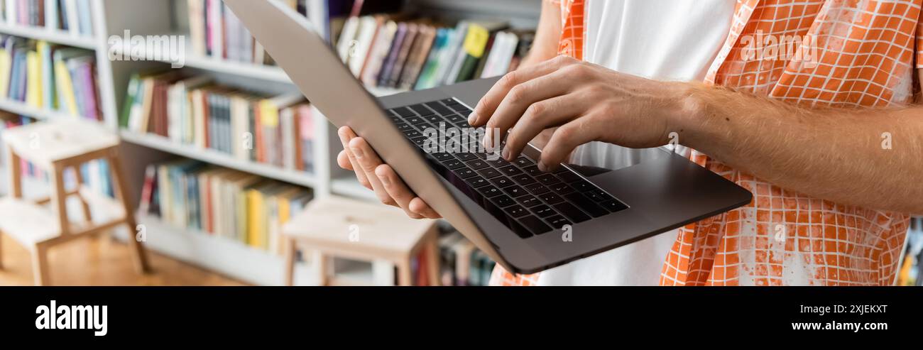 Young man using laptop in library. Stock Photo