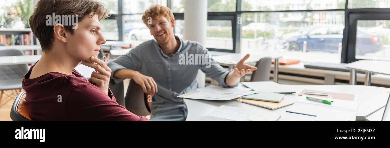 Two young male students deep in study at a library table. Stock Photo