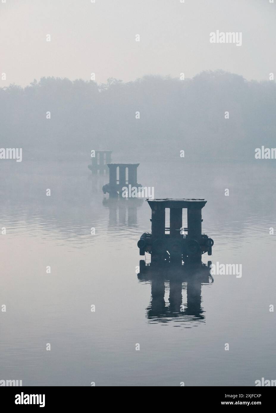 Pillars in water. Row of metal pillars near bridge construction site. Dense for over the river. Stock Photo