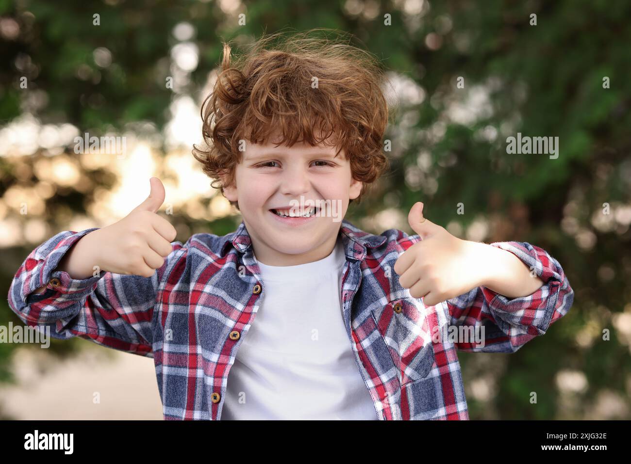 Portrait of cute little boy showing thumbs up outdoors Stock Photo - Alamy