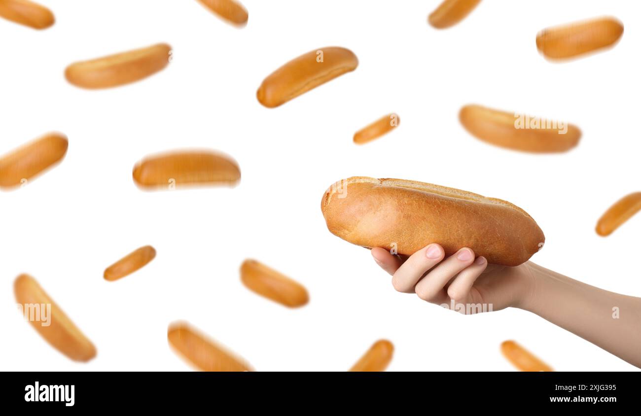 Woman holding hot dog bun against flying ones on white background Stock Photo