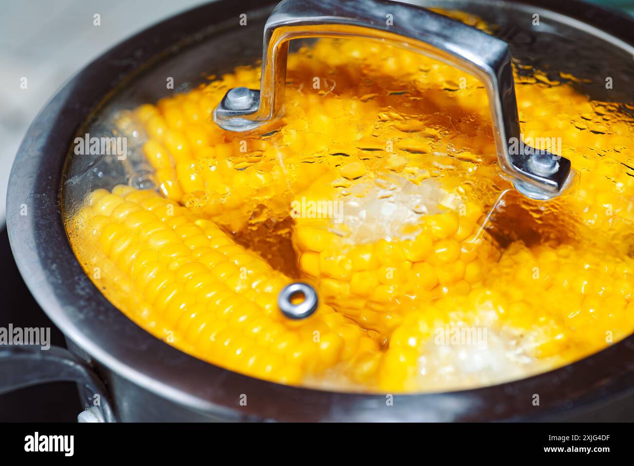 Pot of corn is boiling on a stove. The corn is yellow and he is cooked ...