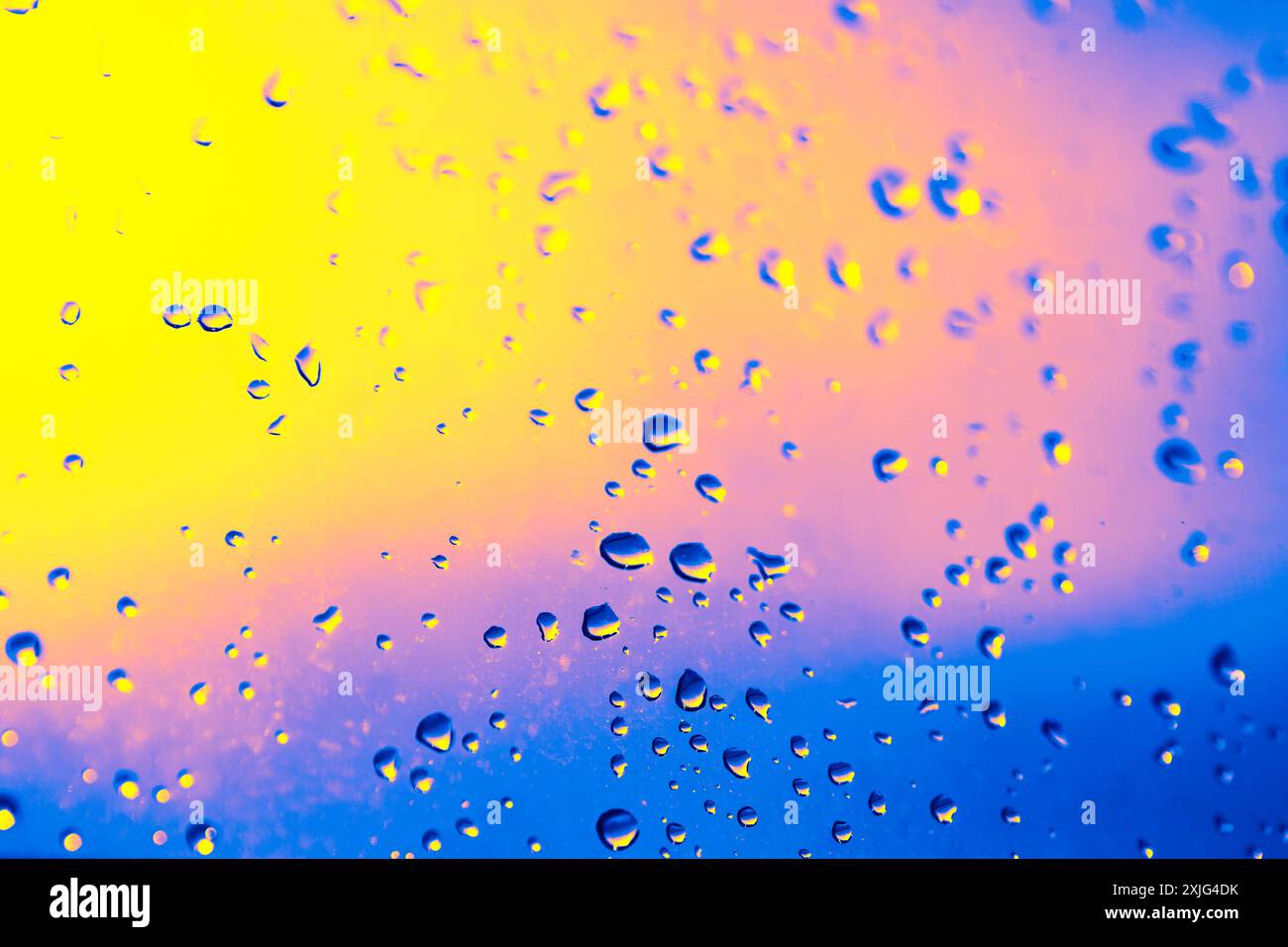 Window with raindrops on it. The raindrops are scattered all over the window, creating a blurry and hazy effect. Scene is calm and peaceful, as the ra Stock Photo