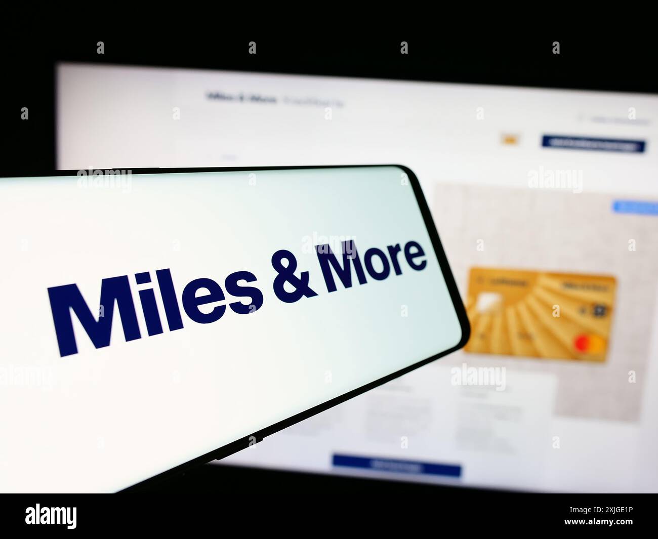 Mobile phone with logo of frequent-flyer program Miles and More (Lufthansa) in front of business website. Focus on center-left of phone display. Stock Photo