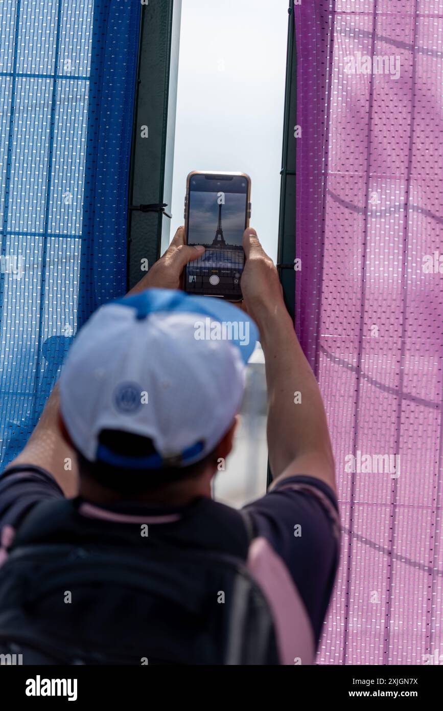 A tourist photographs the Eiffel Tower through a fence at Trocadéro Square, which has limited