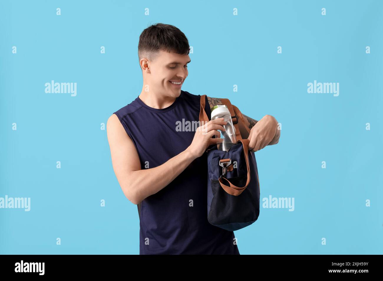 Sporty young man with bottle of water and bag on blue background Stock ...