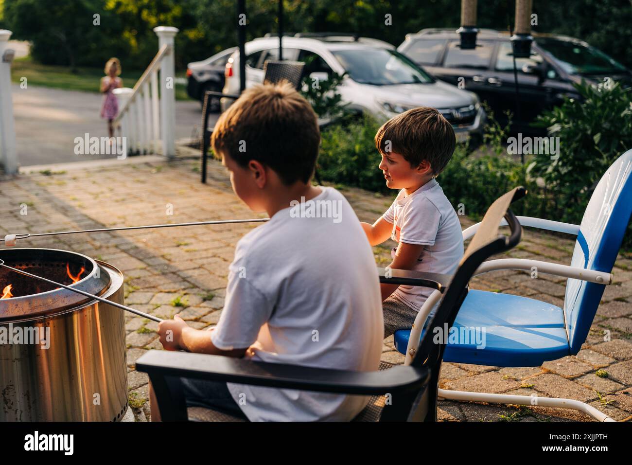 Boys roasting marshmallows on fire pit in backyard patio Stock Photo
