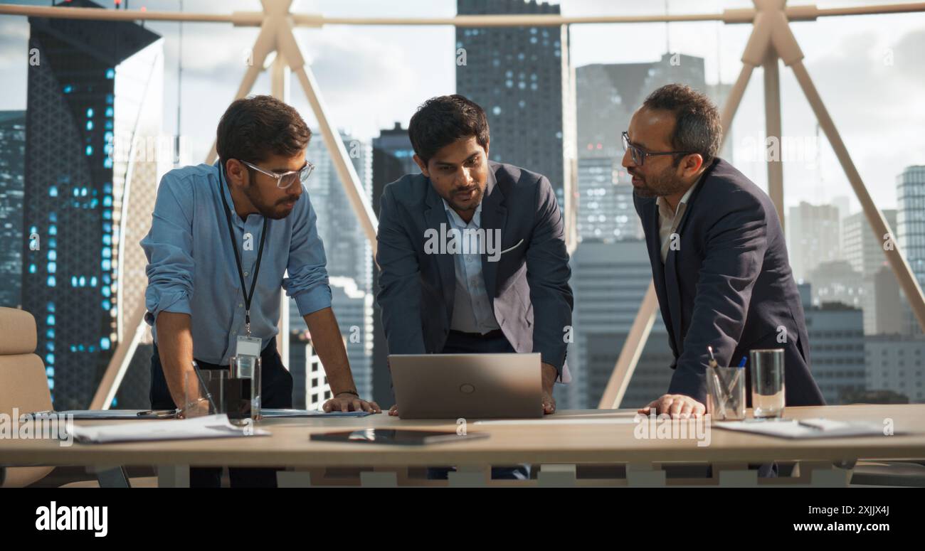 Cinematic Footage of a Successful Indian CEO Making a Presentation on a Laptop to a Board of Directors During a Corporate Meeting. South Asian Business Partners Discussing International Markets Stock Photo