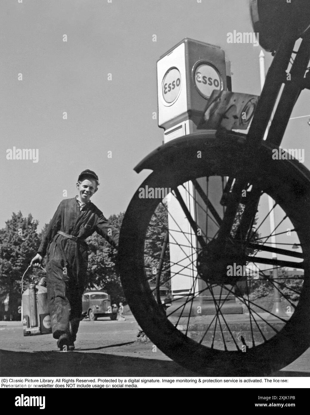 Esso petrol station in the 1950s. A young man is looking service minded ...