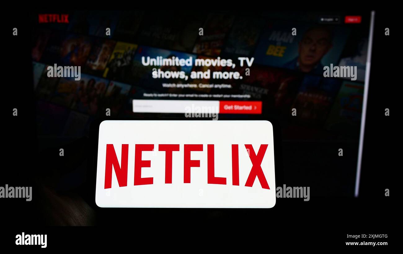 Stuttgart, Germany, 07-16-2022: Person holding cellphone with logo of US video streaming company Netflix Inc. on screen in front of business webpage. Stock Photo