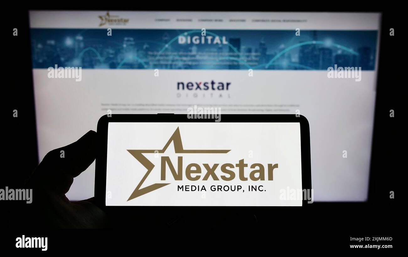 Stuttgart, Germany, 09-04-2022: Person holding smartphone with logo of US television company Nexstar Media Group Inc. on screen in front of website. Stock Photo