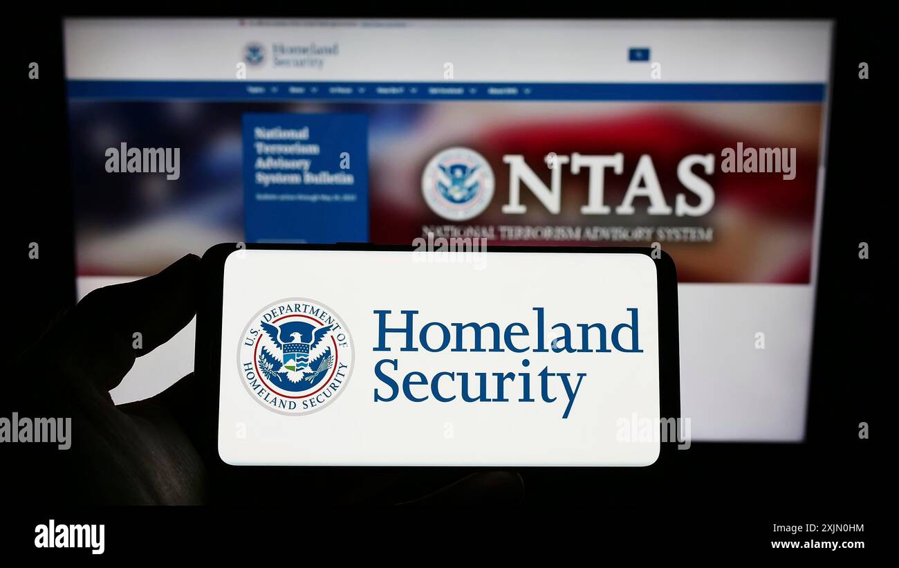 Stuttgart, Germany, 01-13-2023: Person holding mobile phone with seal of American Department of Homeland Security (DHS) on screen in front of web Stock Photo