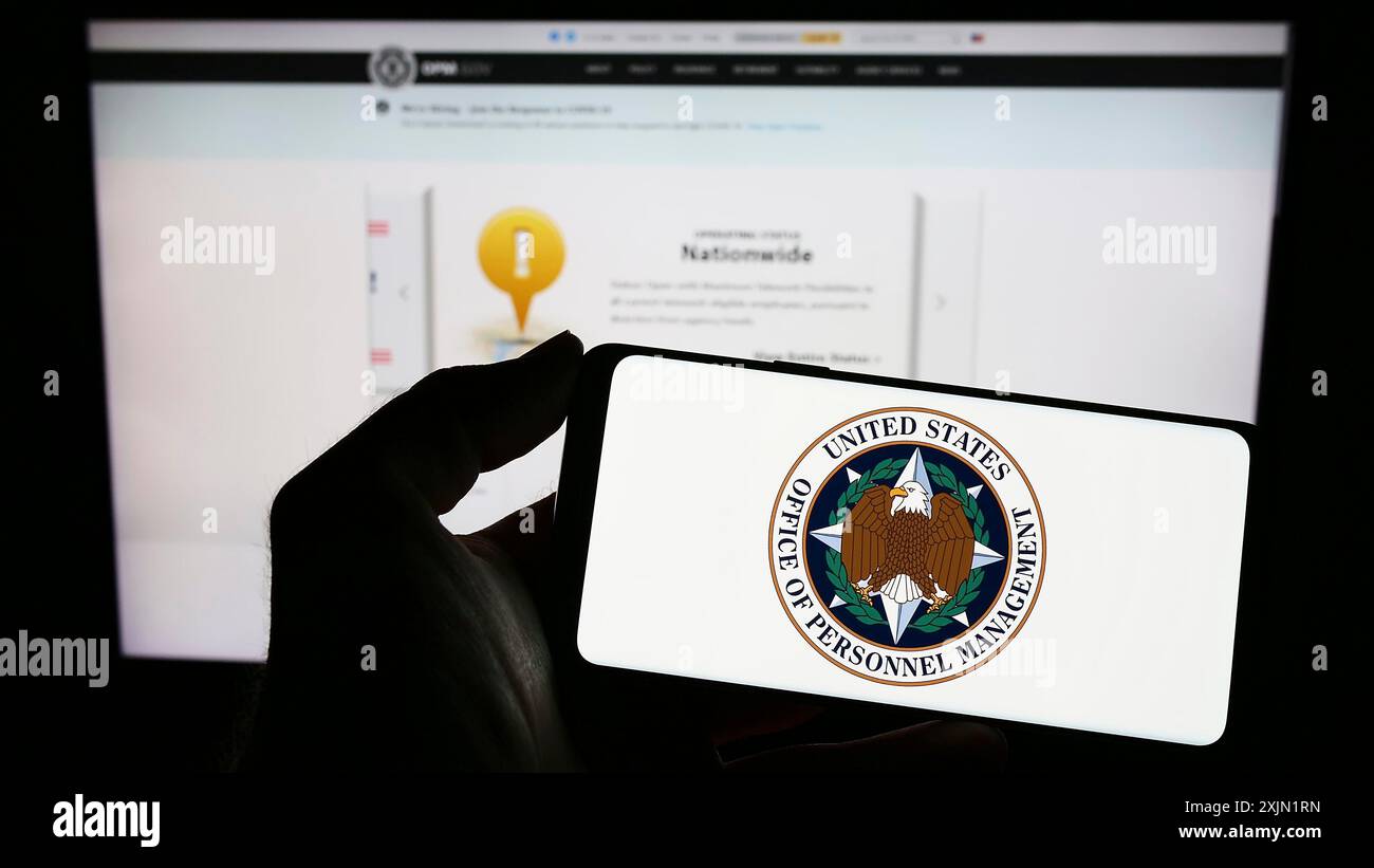 Stuttgart, Germany, 01-22-2023: Person holding mobile phone with seal of US Office of Personnel Management (OPM) on screen in front of web page. Stock Photo