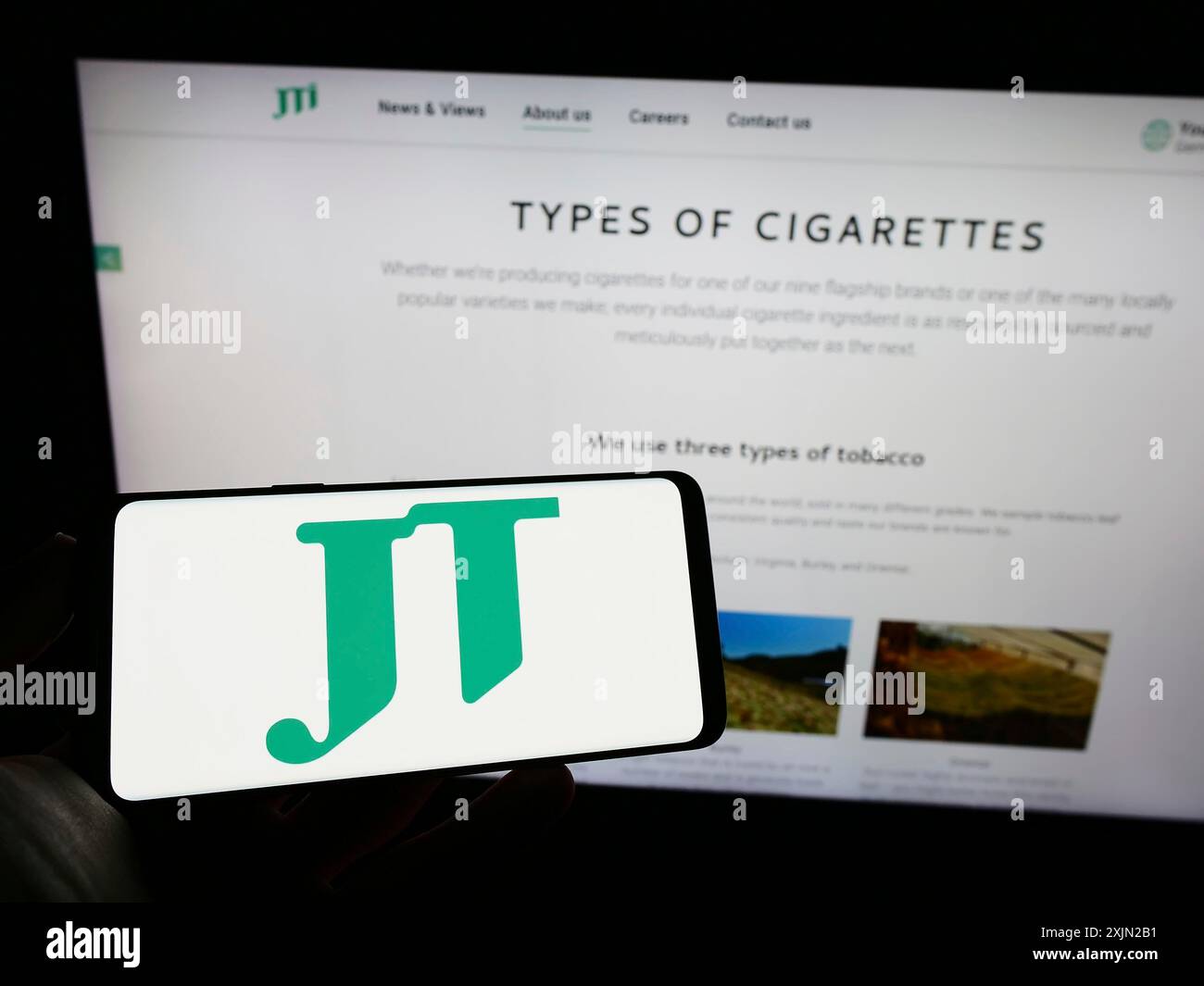 Stuttgart, Germany, 03-07-2023: Person holding cellphone with logo of cigarette company Japan Tobacco Inc. (JT) on screen in front of business web Stock Photo