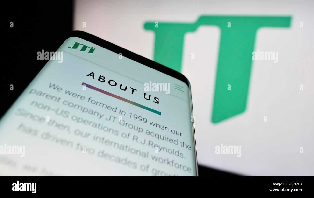 Stuttgart, Germany, 03-07-2023: Mobile phone with website of cigarette company Japan Tobacco Inc. (JT) on screen in front of business logo. Focus on Stock Photo