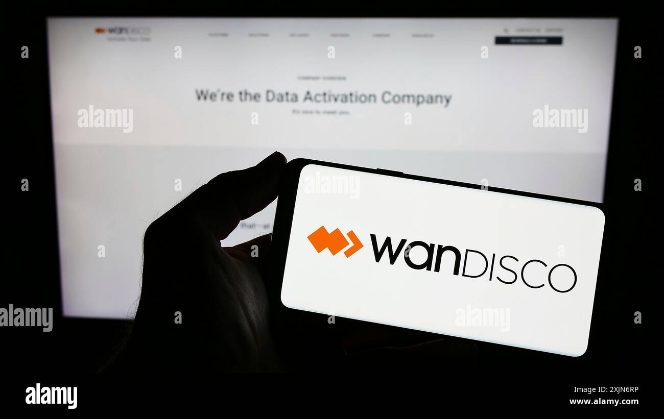 Stuttgart, Germany, 03-17-2023: Person holding smartphone with logo of software company WANdisco plc on screen in front of website. Focus on phone Stock Photo