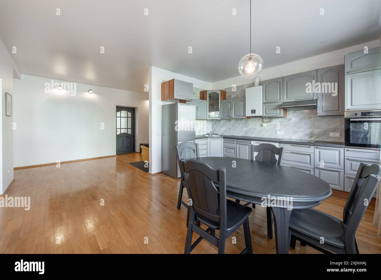 Classic White Kitchen Interior and Dinning Table. Oven, Kettle, Microwave and Glass. Plates on the Table. Minimalistic Interior Design. Stock Photo