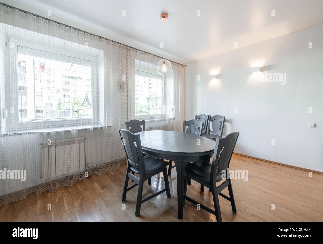 Classic White Kitchen Interior and Dinning Table. Oven, Kettle, Microwave and Glass. Plates on the Table. Minimalistic Interior Design. Stock Photo