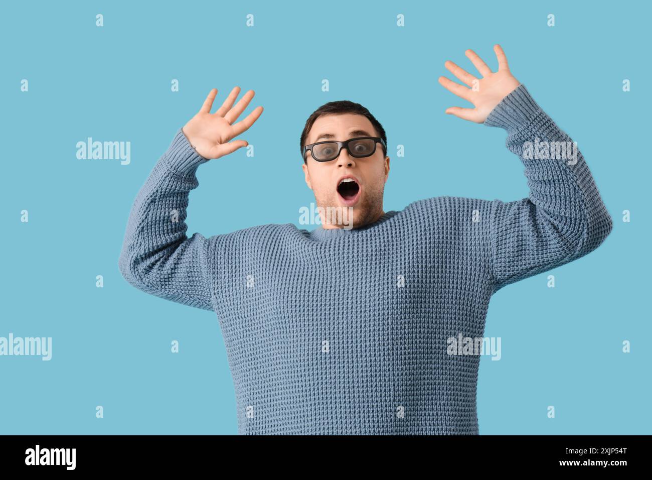 Scared young man in 3D glasses on blue background Stock Photo
