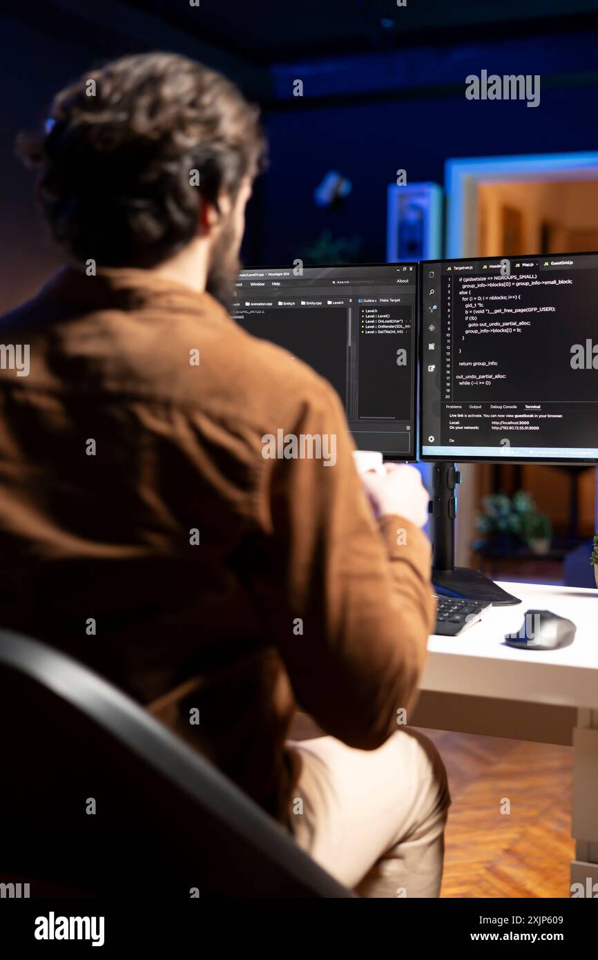 Computer engineer doing software quality assurance, reading source code on screen before implementing it. IT admin inspecting coding on desktop PC, looking to fix potential issues Stock Photo