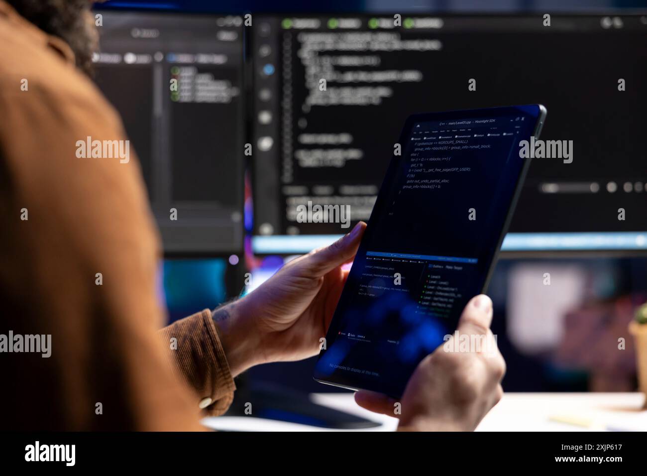 Computer scientist doing software quality assurance using tablet, reading source code before implementing it. Developer inspecting coding on portable device, looking to fix potential issues Stock Photo