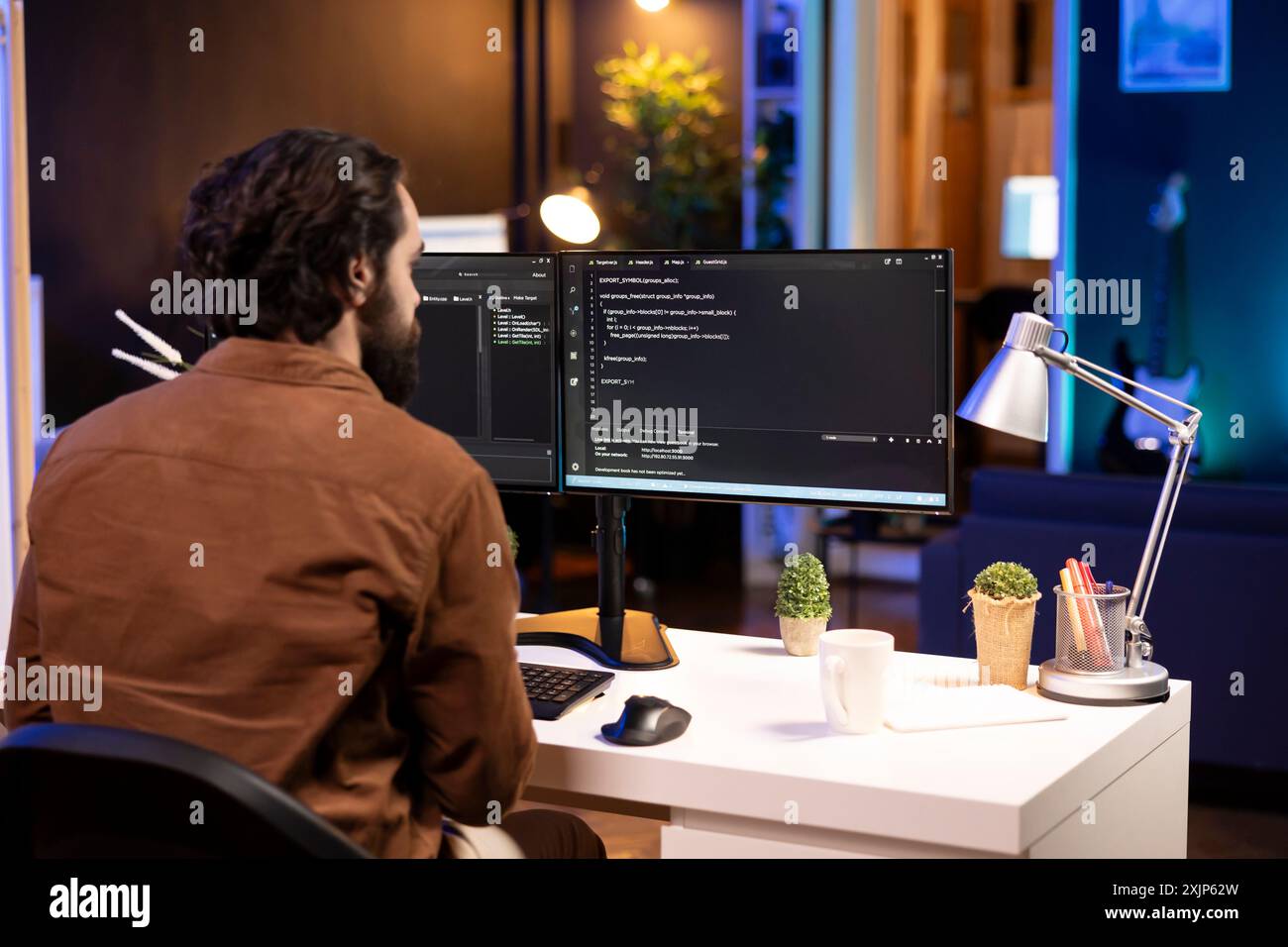 Computer operator doing software debugging on PC at home, checking broken lines of code displayed on monitors. IT expert in apartment fixing coding problems, typing on keyboard Stock Photo