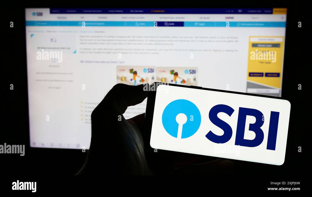 Stuttgart, Germany, 06-30-2023: Person holding cellphone with logo of Indian company State Bank of India (SBI) on screen in front of business Stock Photo